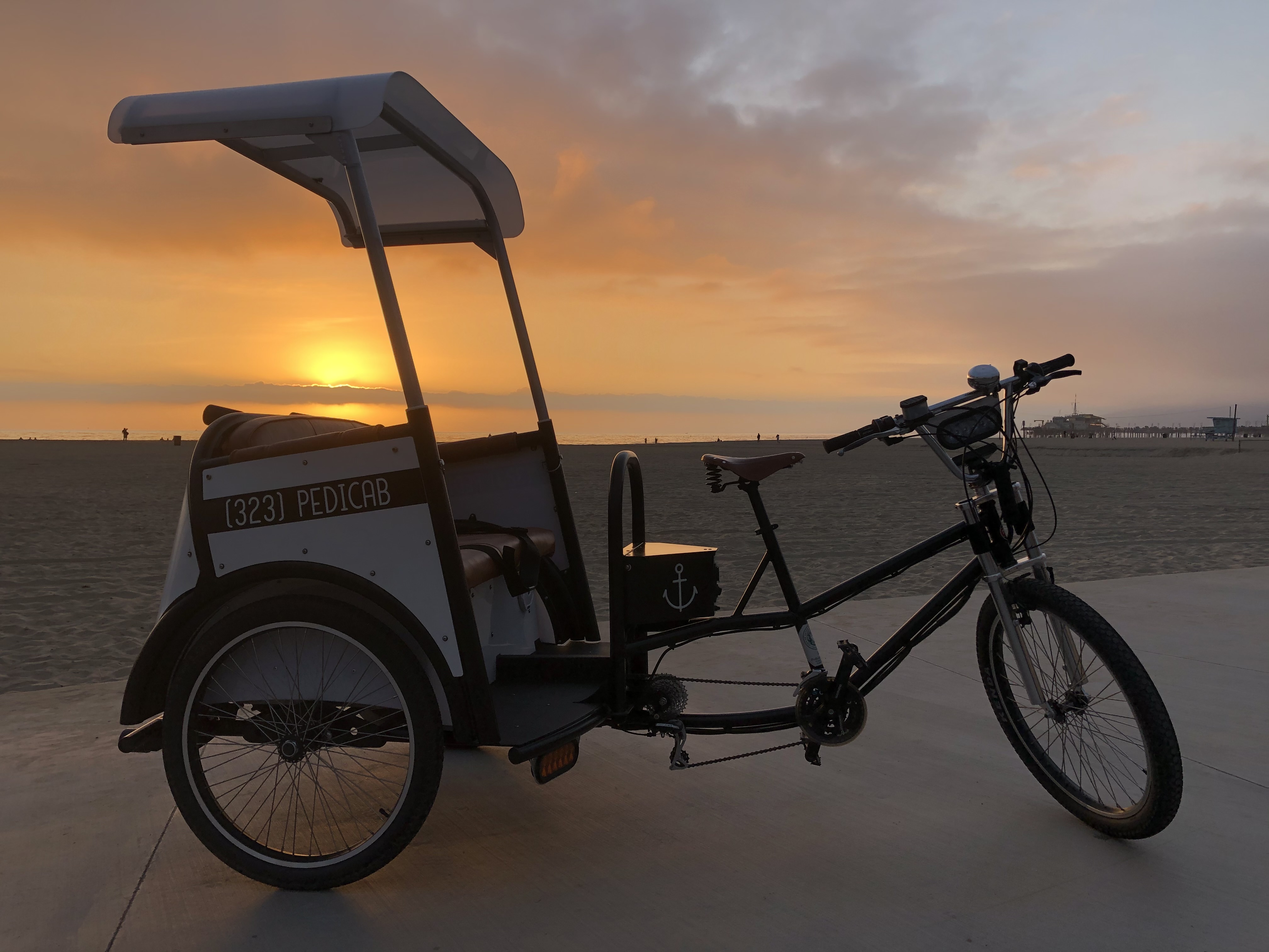 A Beach Buggy electric pedicab at sunset on the Santa Monica Pier boardwalk.